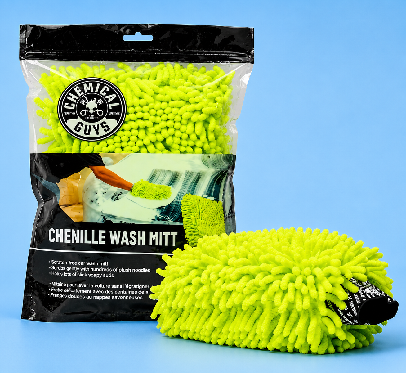 A bright lime green Chemical Guys chenille car wash mitt next to its retail packaging on a solid blue background.