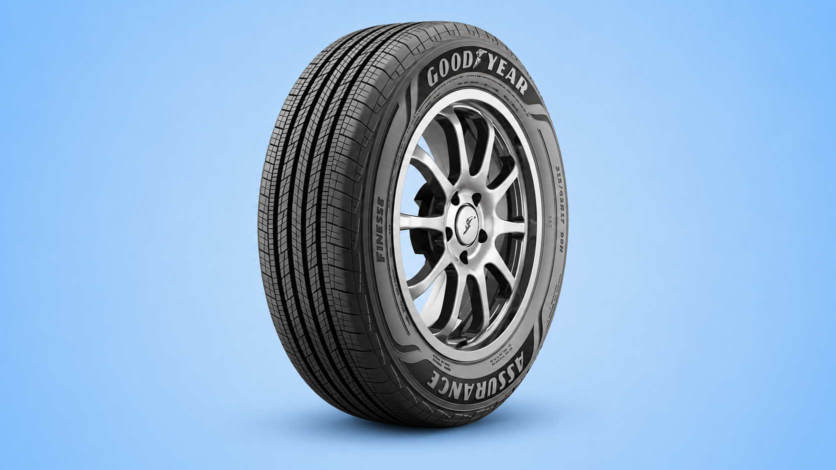 A Goodyear Assurance Finesse car tire mounted on a silver rim against a blue background.