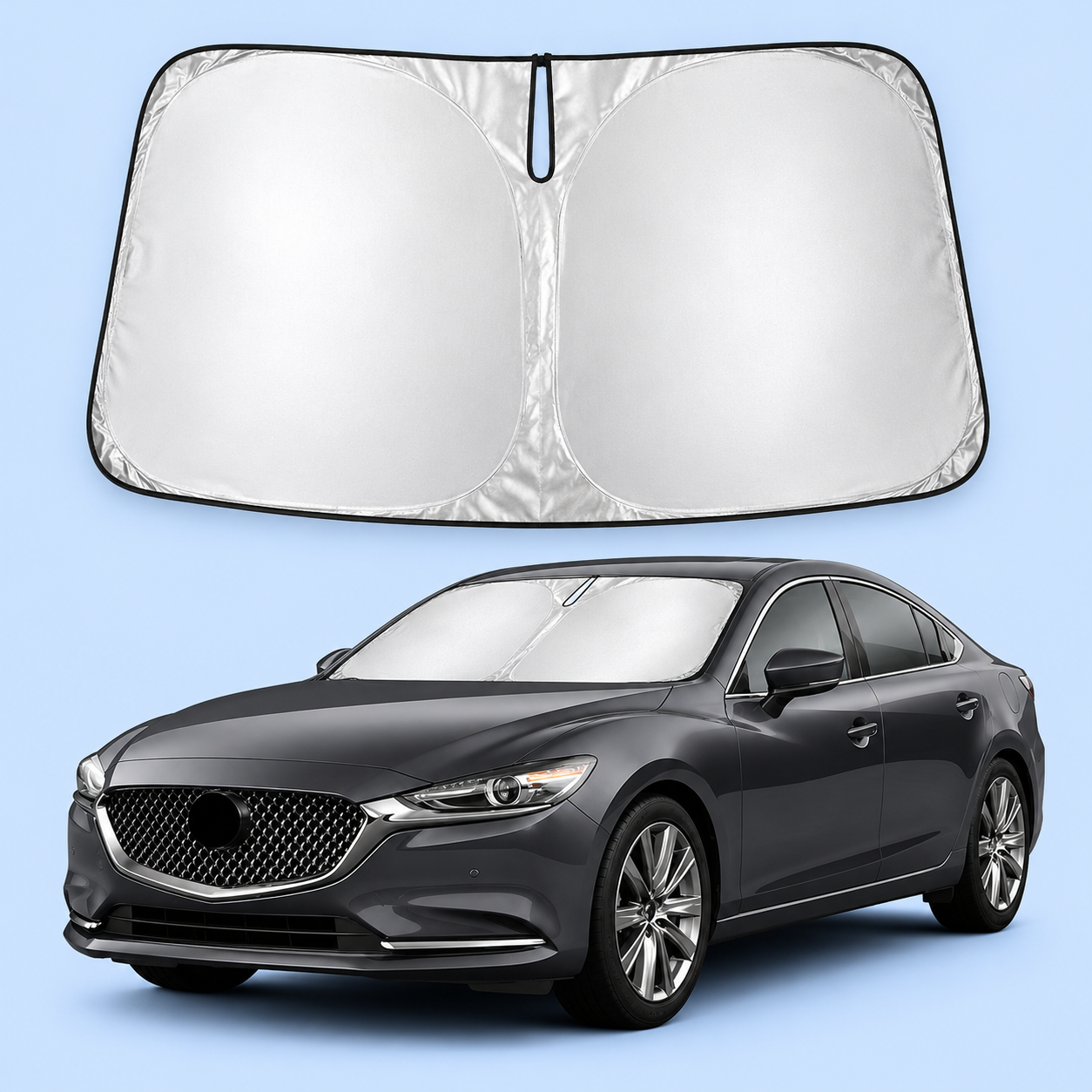 A silver reflective car windshield sun shade shown open and installed inside a gray sedan.